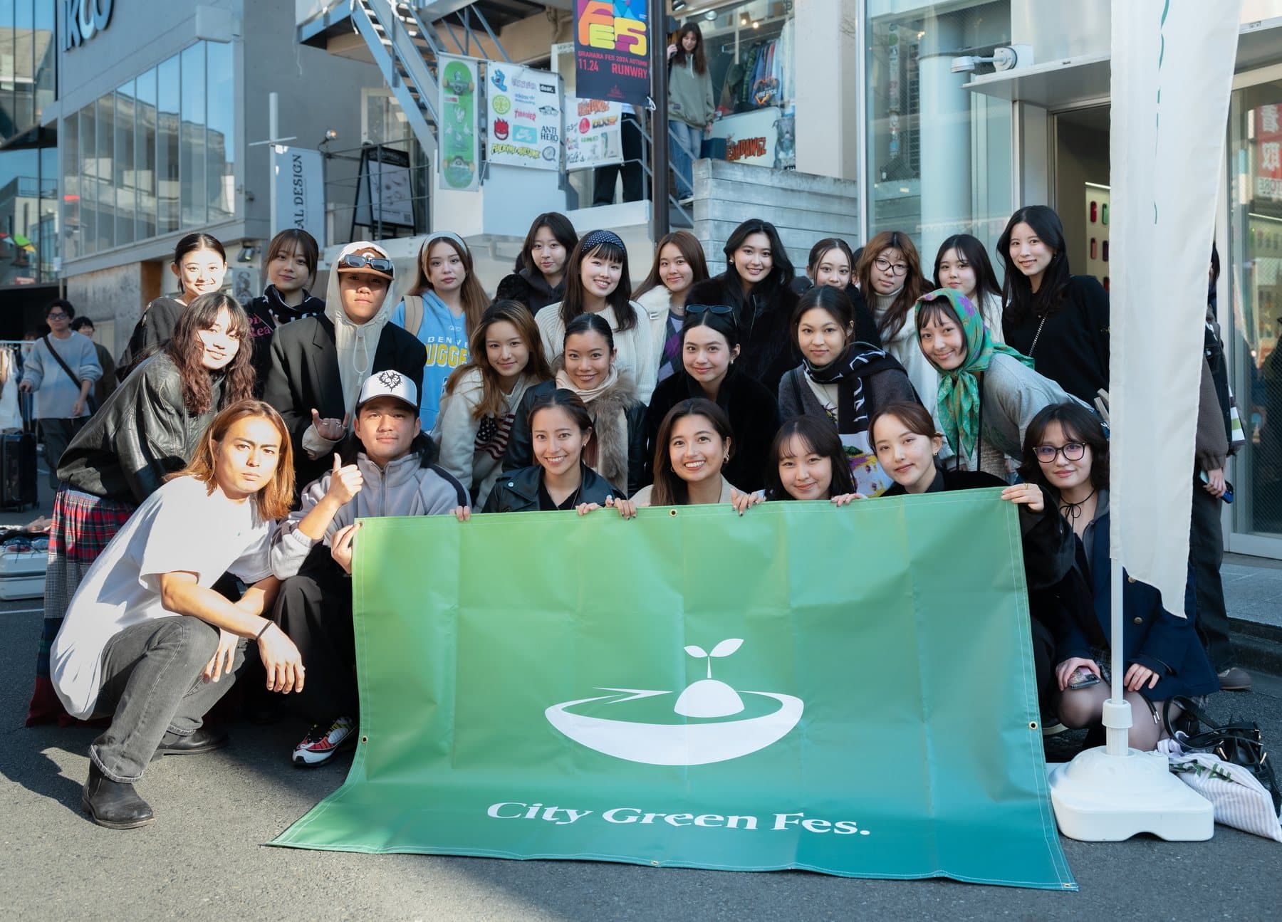 Young people gathered around a City Green Fes. flag in Harajuku